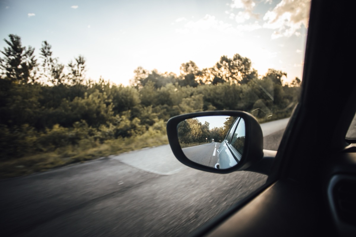 Wing mirror reflecting the road behind a moving car