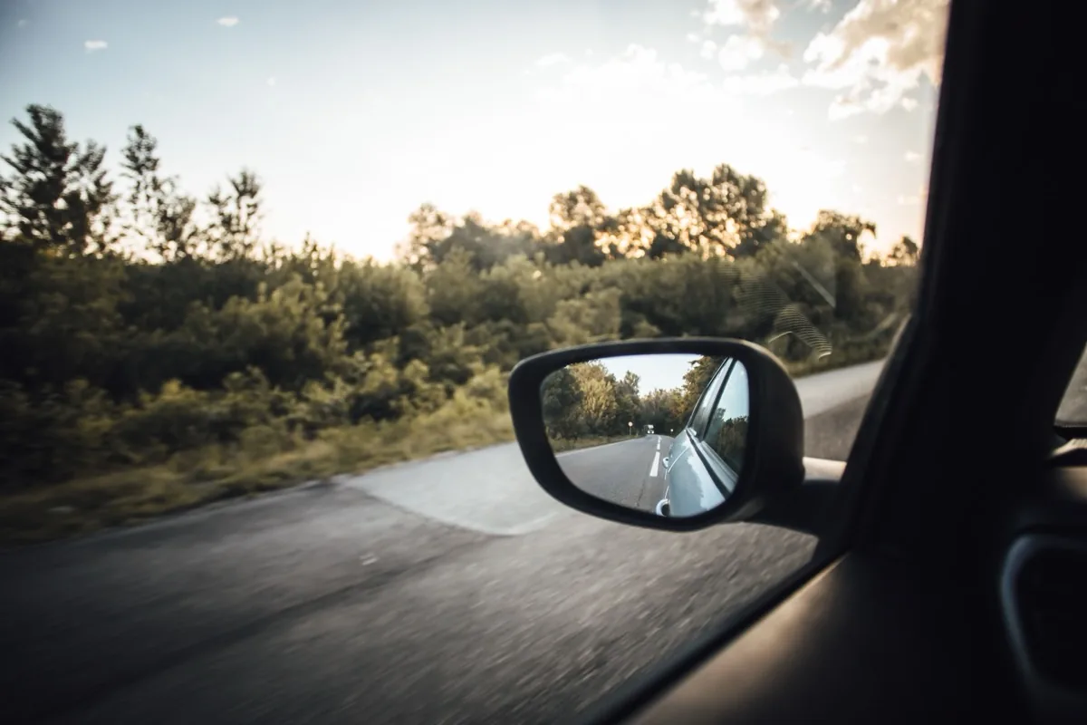 Wing mirror reflecting the road behind a moving car