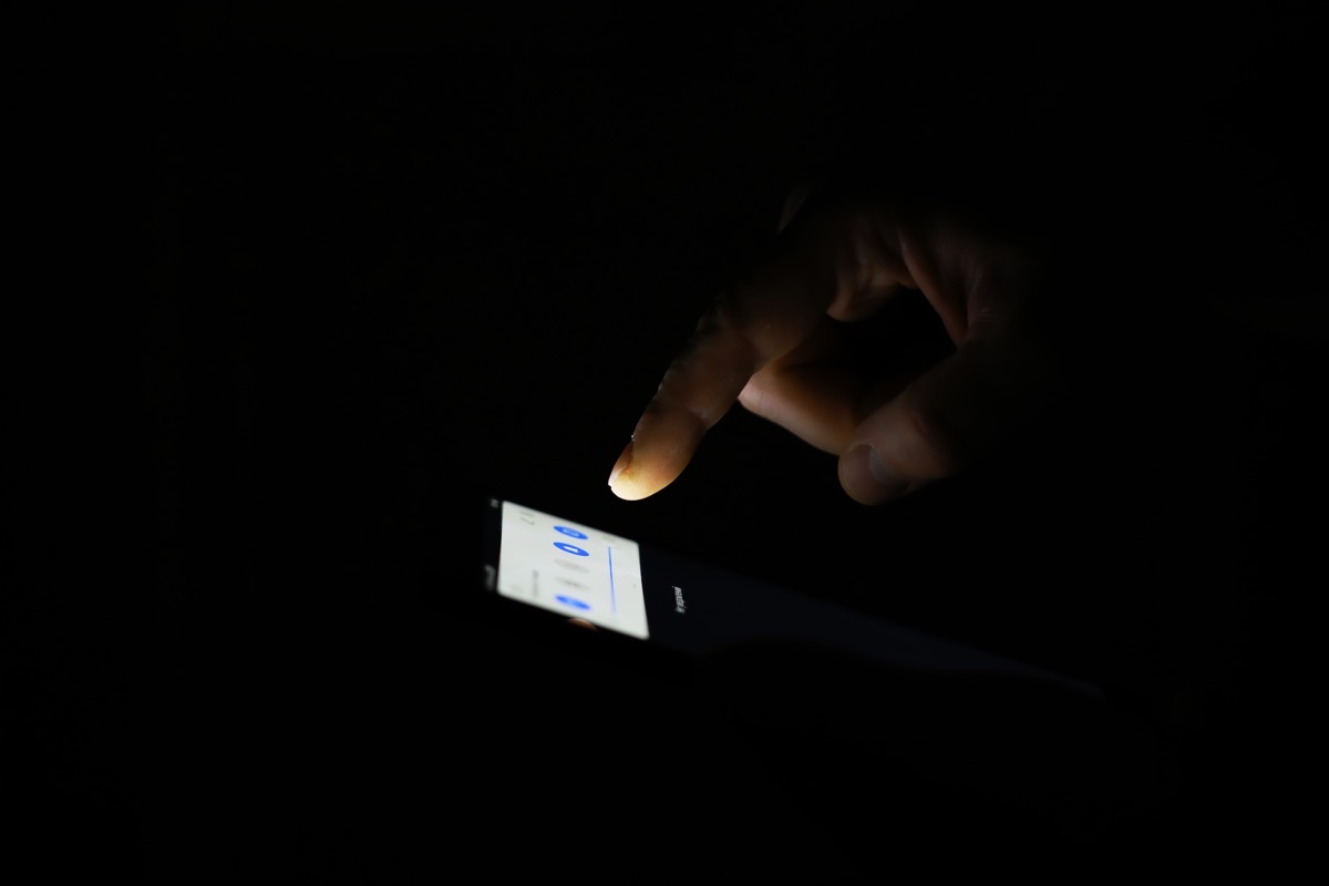 Hand using a smartphone in a dark room