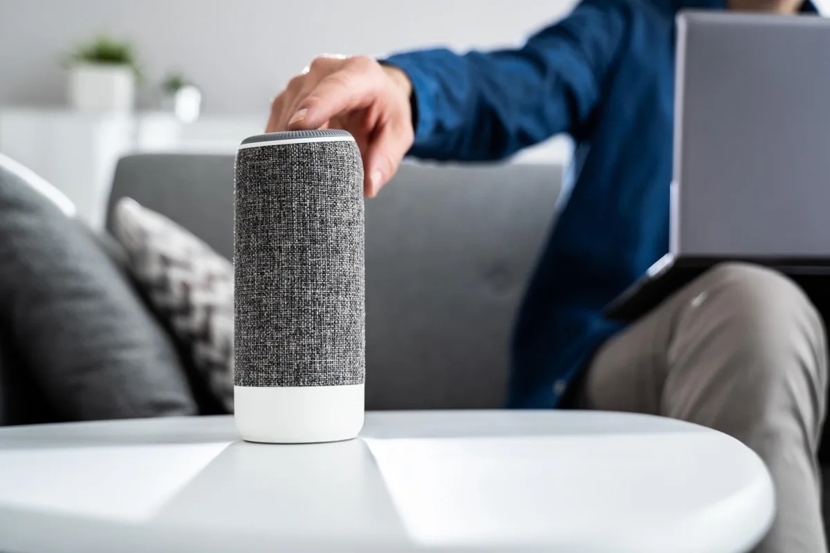 Hand reaching for a voice assistant speaker